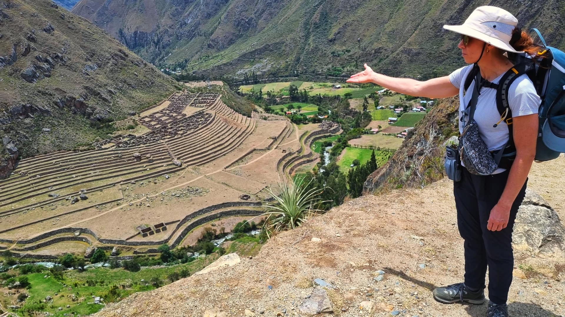 A tourist pointing at the Sacred Valley of the Incas, surrounded by dramatic mountain landscapes and lush greenery under a clear blue sky. A tourist pointing at the Sacred Valley of the Incas, surrounded by dramatic mountain landscapes and lush greenery under a clear blue sky.