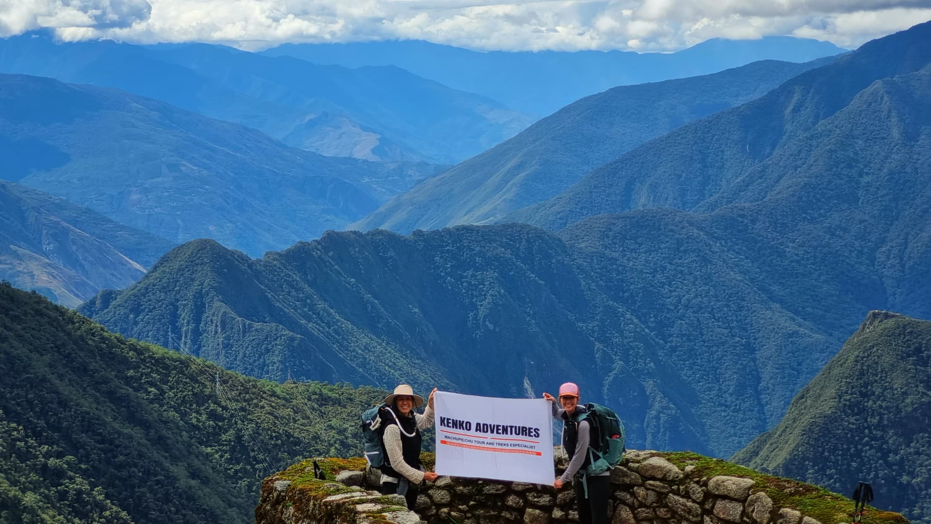 A group of tourists standing at a viewpoint in the Sacred Valley, admiring the panoramic landscape of terraced fields and mountains under a partly cloudy sky. A group of tourists standing at a viewpoint in the Sacred Valley, admiring the panoramic landscape of terraced fields and mountains under a partly cloudy sky.