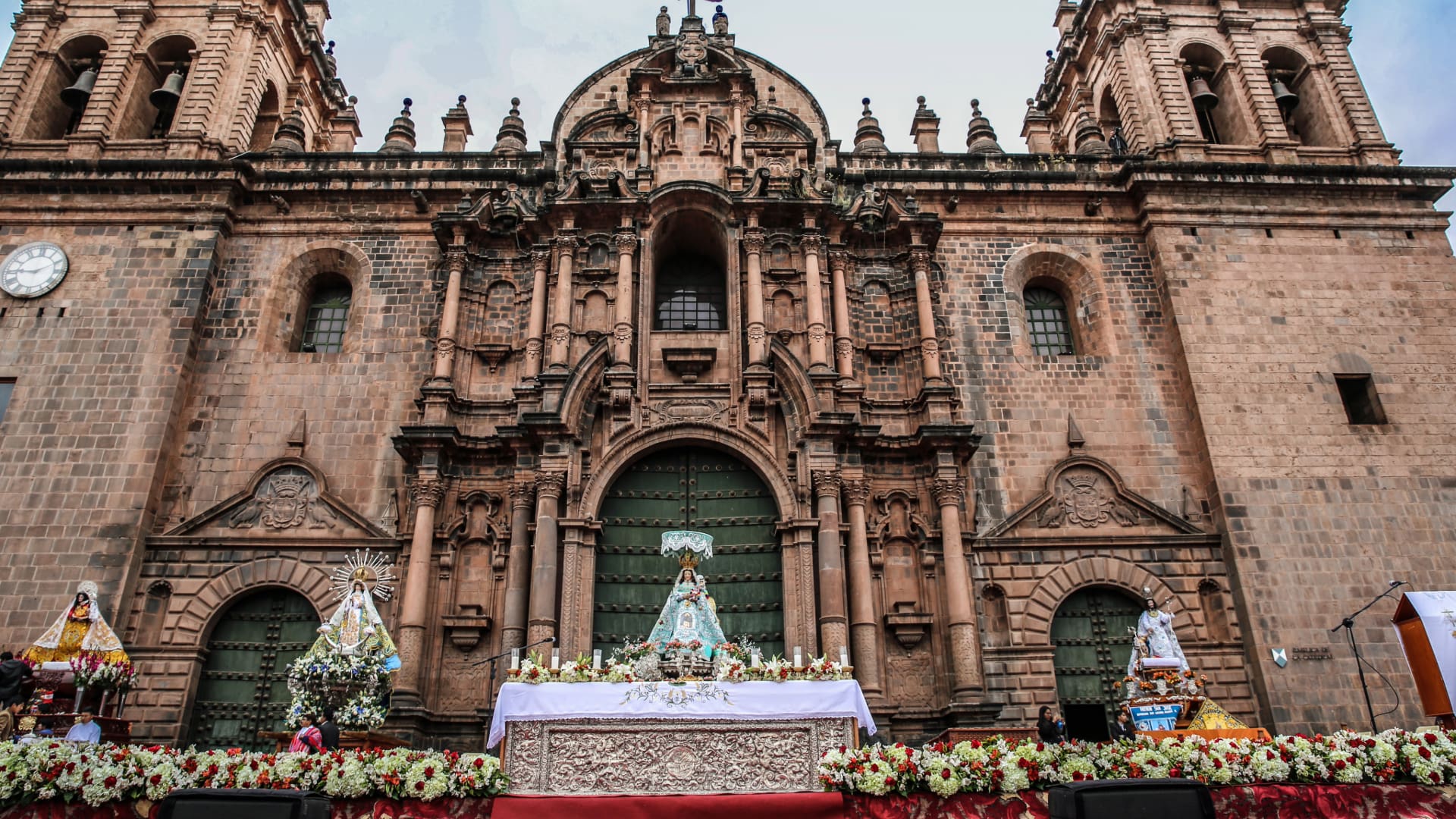 Images of saints and virgins in front of Cusco Cathedral during the Corpus Christi festival, surrounded by flowers and devotees - Kenko Adventure