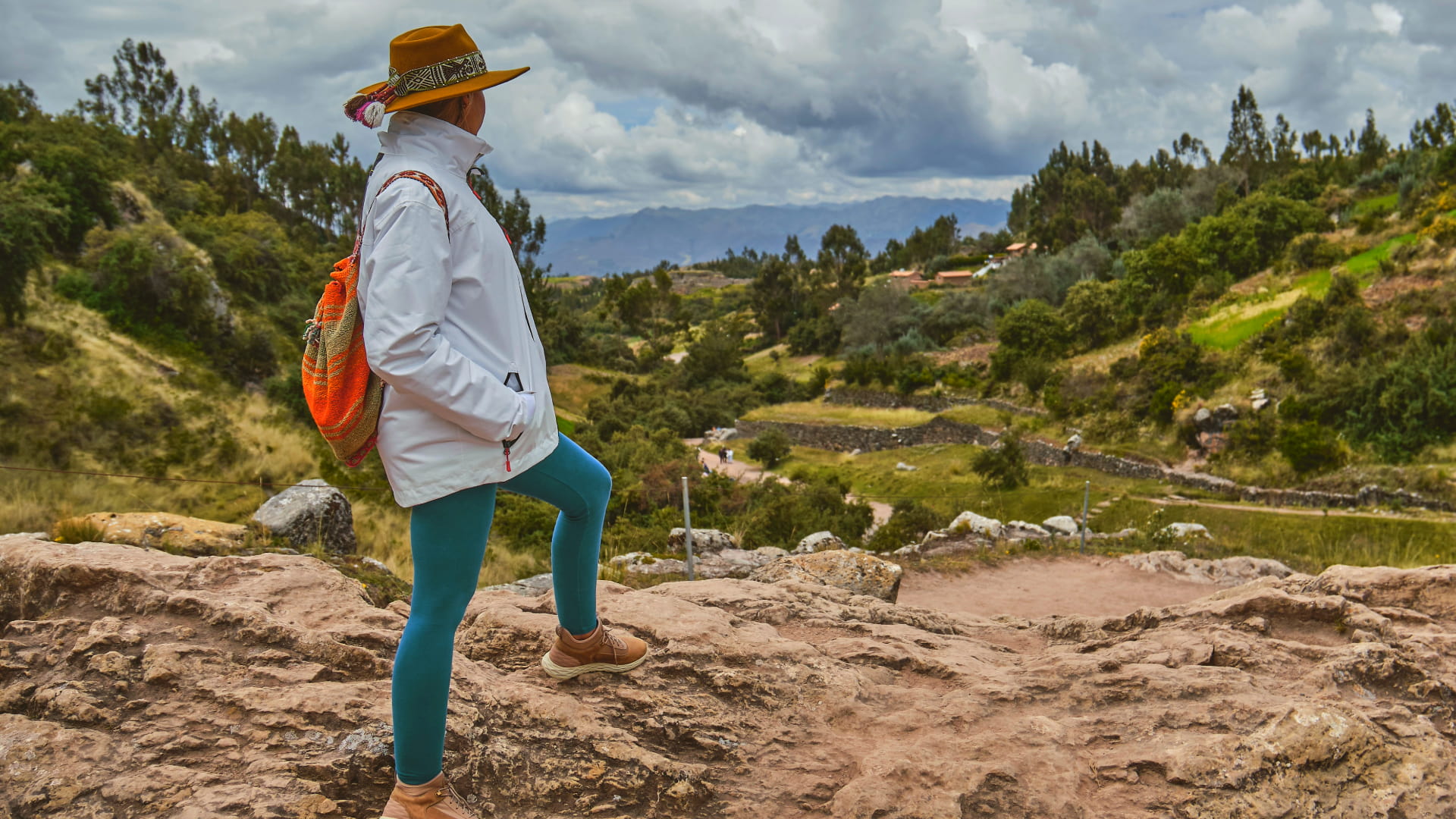 Traveler with an Andean backpack and hat overlooking the scenic valleys near Tambomachay, Cusco - Kenko Adventure