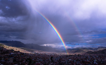 A rainbow over Cusco appears as the rain falls.