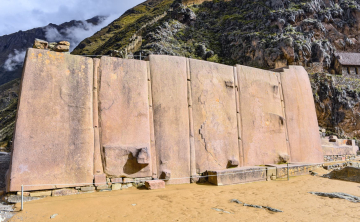 Close-up of large Inca stones at Ollantaytambo, showcasing their precise fitting and impressive size, set against the backdrop of ancient terraces and mountains.