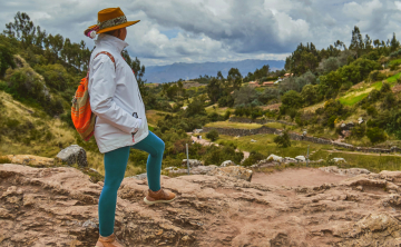 Traveler with an Andean backpack and hat overlooking the scenic valleys near Tambomachay, Cusco - Kenko Adventure