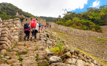 Hikers trekking the Inca Trail through Andean mountains and ancient archaeological sites, on their way to Machu Picchu at sunrise.