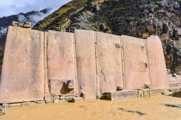 Close-up of large Inca stones at Ollantaytambo, showcasing their precise fitting and impressive size, set against the backdrop of ancient terraces and mountains.