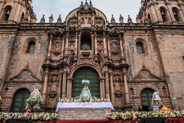 Images of saints and virgins in front of Cusco Cathedral during the Corpus Christi festival, surrounded by flowers and devotees - Kenko Adventure