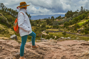 Traveler with an Andean backpack and hat overlooking the scenic valleys near Tambomachay, Cusco - Kenko Adventure