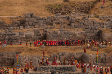 Inti Raymi ceremony at Sacsayhuamán with participants in traditional costumes and ancient stone ruins, Kenko Adventures